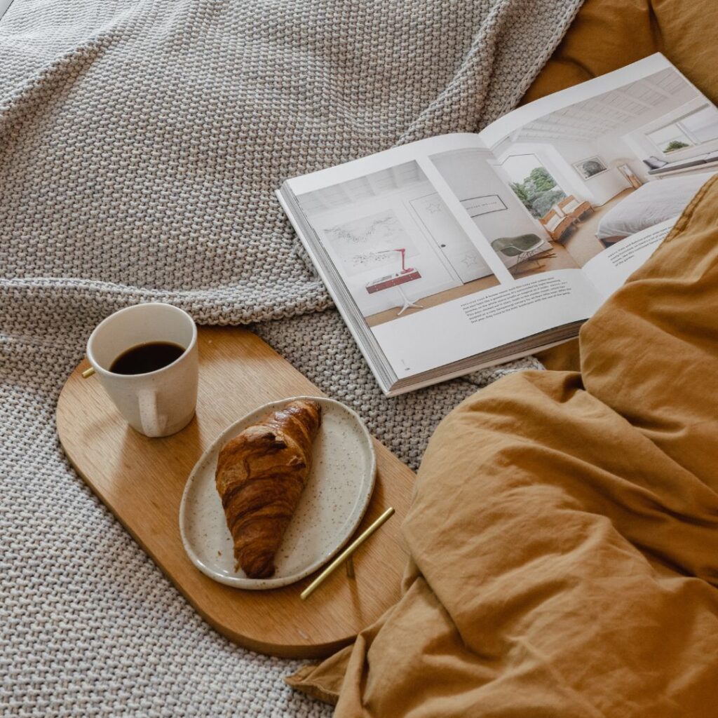 cup of coffee and croissant on bed table